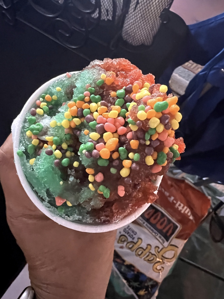 Holding up a vibrant layered candy-topped snoball