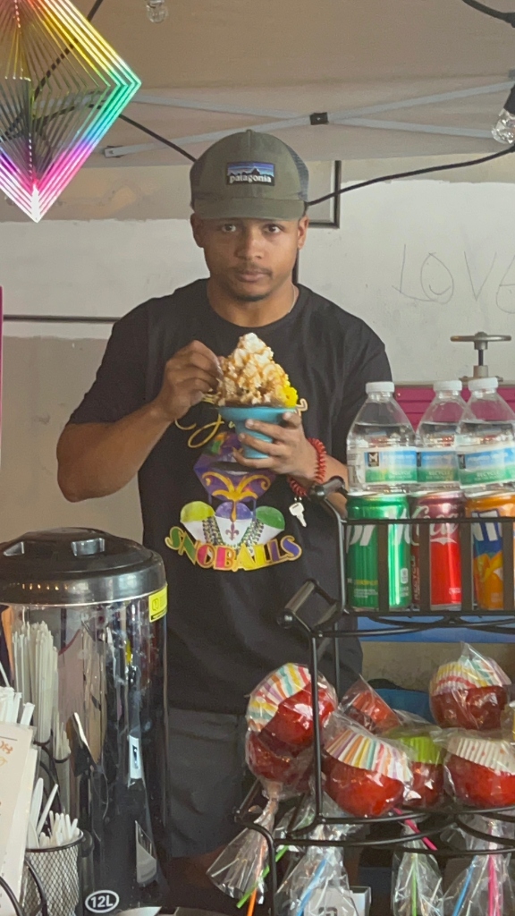 Team member in Seaux Juicy merch shaping a snoball at the stand
